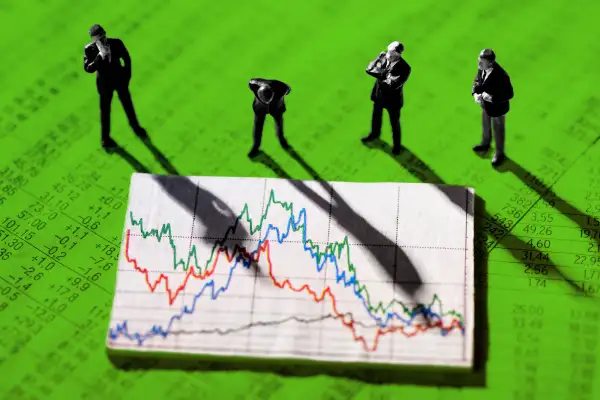 Photo collage of businessmen figurines looking at a stock market chart