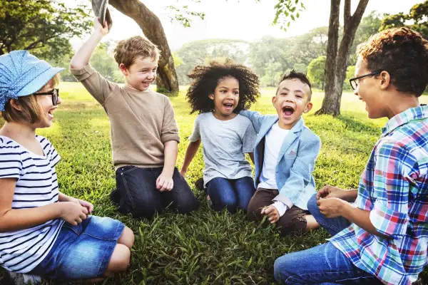 Diverse Group Of Kids Sitting On The Grass In A Park