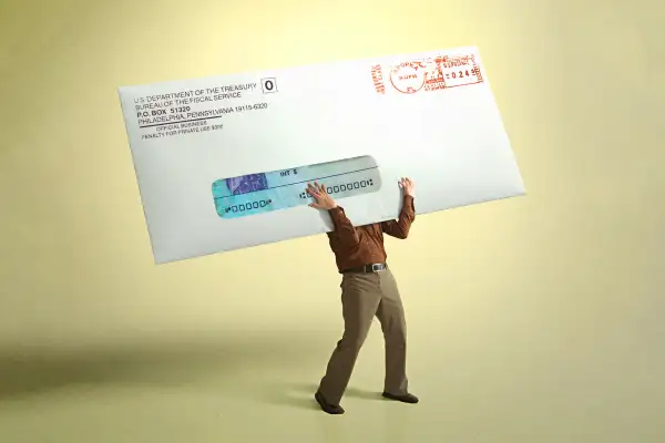 Photo collage of a person holding a giant envelope from the IRS containing a Stimulus Check