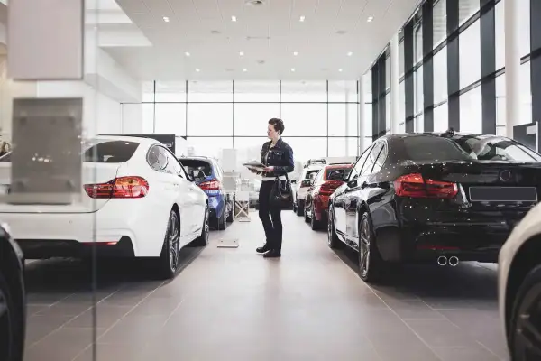 Senior woman holding documents and looking at cars in showroom