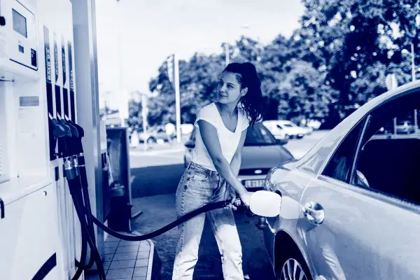 A young woman refueling the gas tank of her car