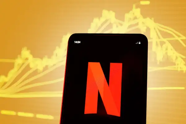 Smartphone showing the Netflix logo with a stock chart in the background