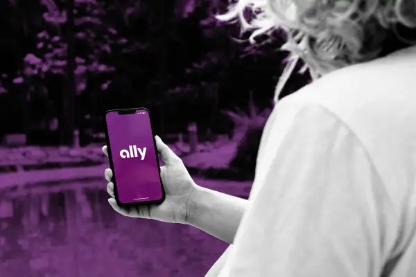Close-up of a person holding a smartphone with the Ally bank app