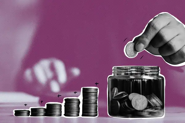 Close-up of a hand inserting coins into a jar