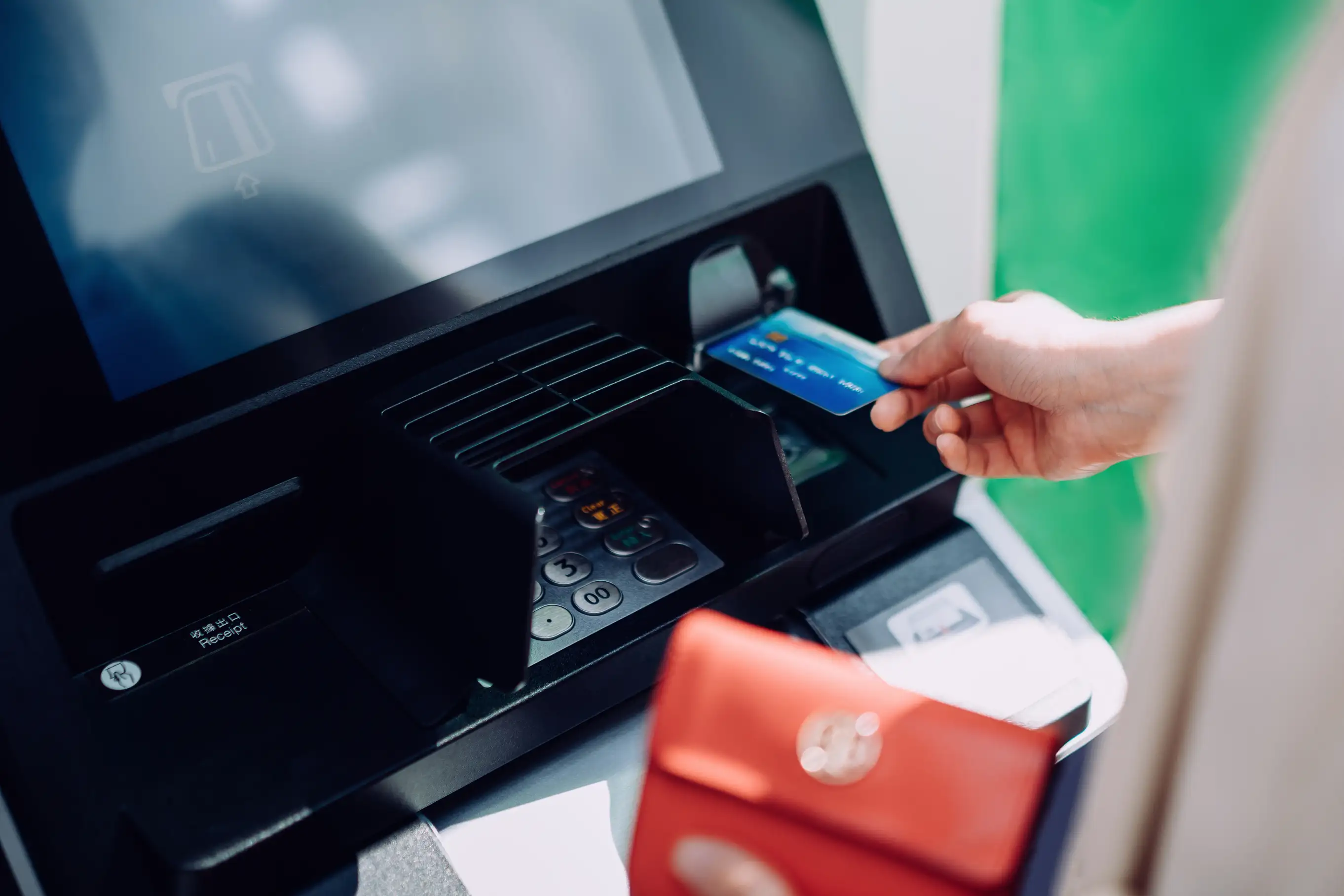 Close up of young woman inserting her bank card into a ATM machine in the city