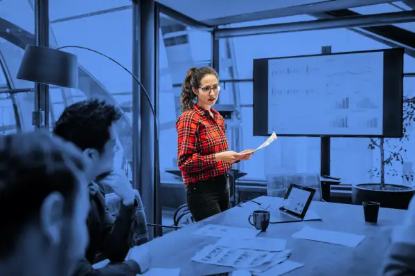 A young woman looking over some charts and data with her colleagues during a management meeting in a contemporary office space.