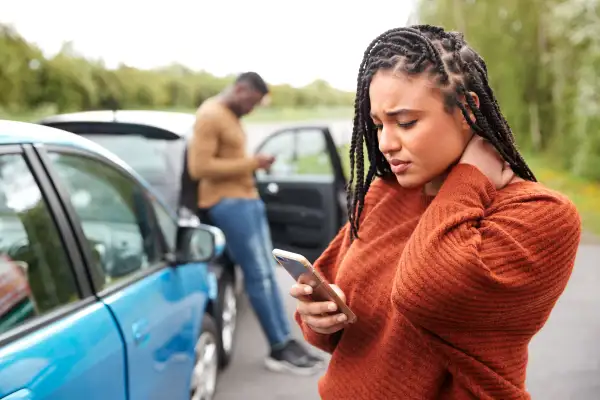 A woman placing a phone call to insurance company after being in a car accident