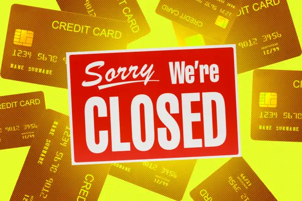 A  Sorry We're Closed  sign with multiple credit cards in the background