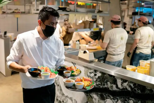 A waiter carries three plates from the kitchen at a Mexican Restaurant