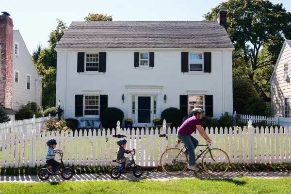 Family riding bike passing by a house