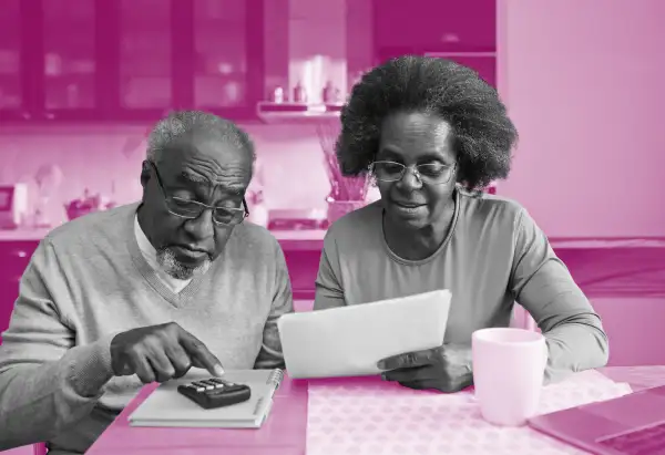 Senior couple looking over bills and a calculator in their kitchen