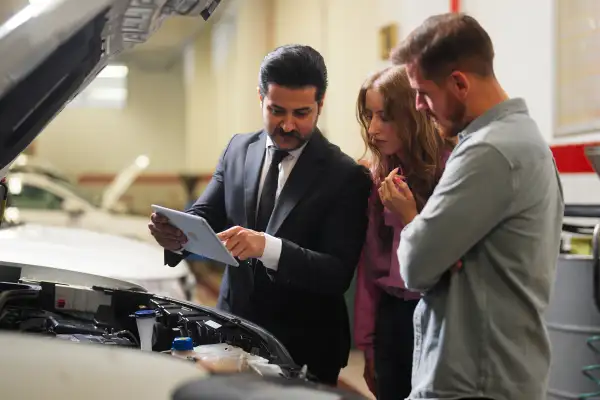 Car insurance expert checking broken car and discussing with couple