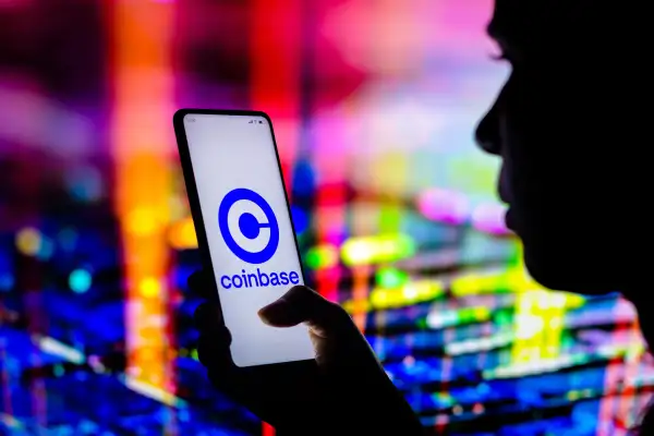 Woman holding a smartphone with coinbase logo on the screen