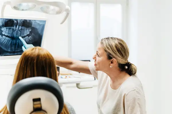 Orthodontist Pointing At Teeth On X-Ray Displayed On Surgery Monitor