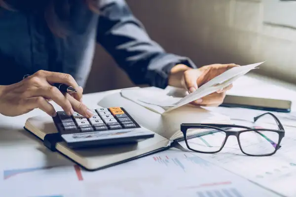 Close-up of a person looking at financial documents while using a calculator