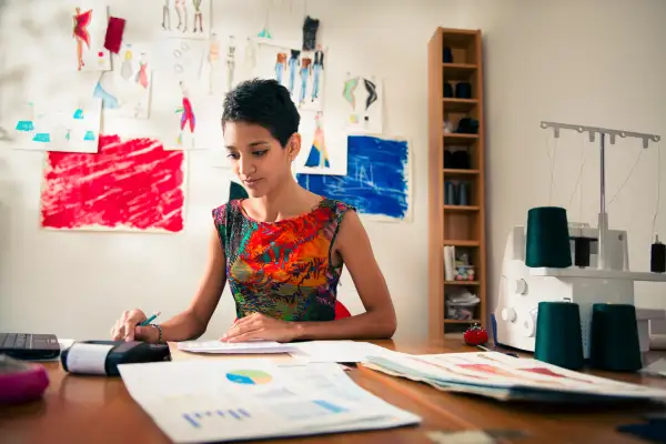 hispanic woman doing budget in fashion designer atelier