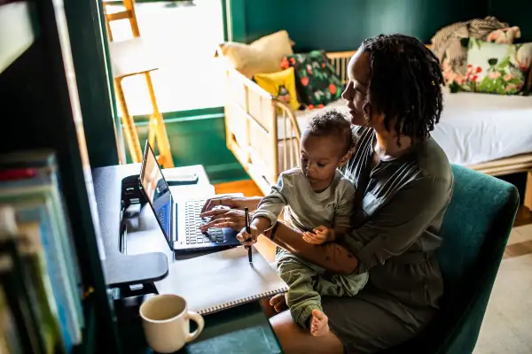 Woman working from home while holding toddler