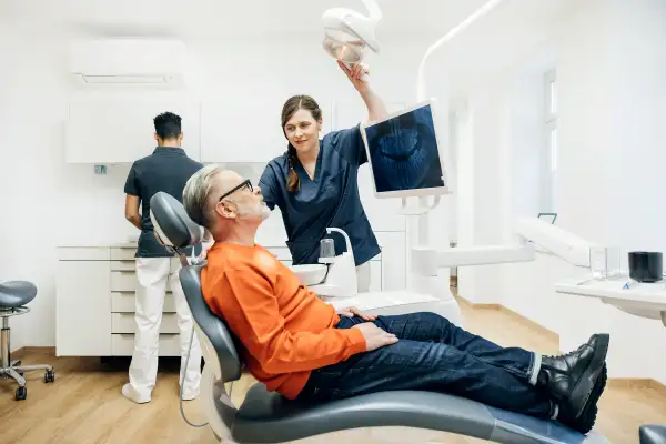 Dental Assistant Adjusting Overhead Light During Check Up On Patient