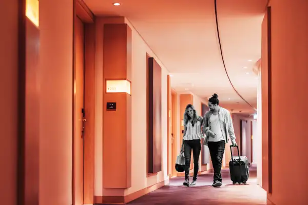 Couple walking with their luggage in the hotel corridor