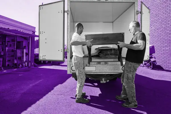 Two men carrying a wooden table into a moving van