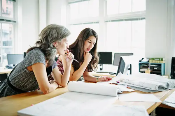 Businesswomen leaning on table discussing plans