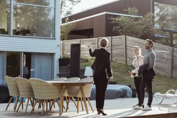 Rear view of female agent showing new property to couple outdoors