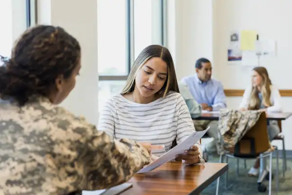 Female soldier explains document to young woman