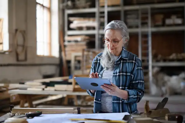 Senior female carpenter using tablet in carpentry workshop.