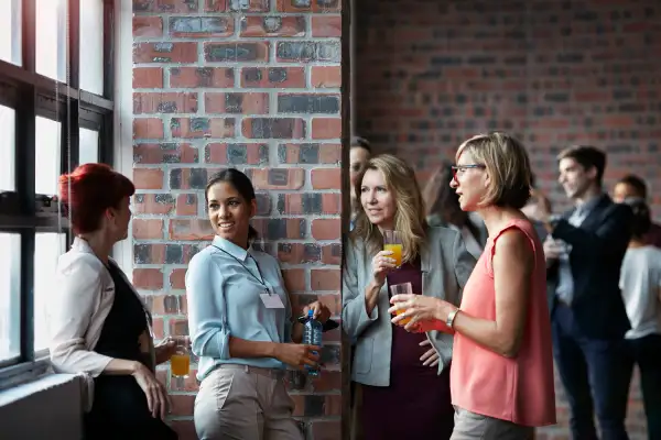 Businesspeople socializing by window of auditorium