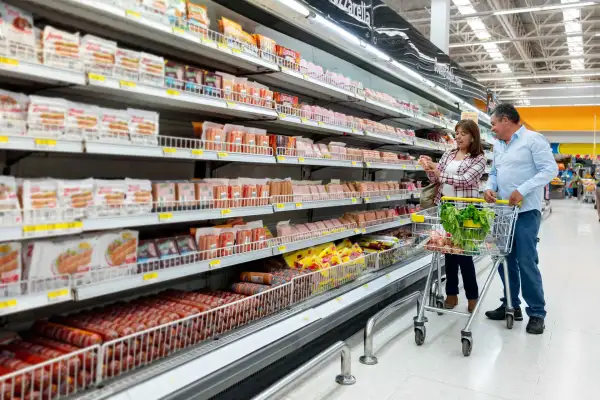 Mature woman showing partner label on refrigerated product at the grocery store both smiling