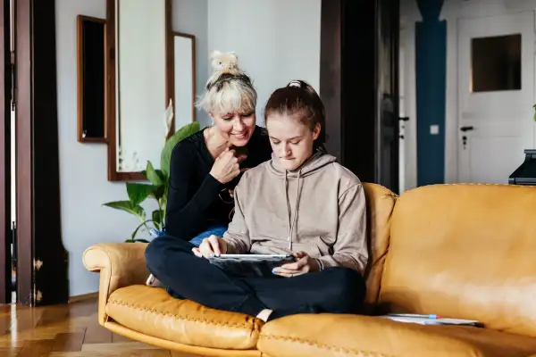 A single mom helping her daughter with some homework in their living room at home together.