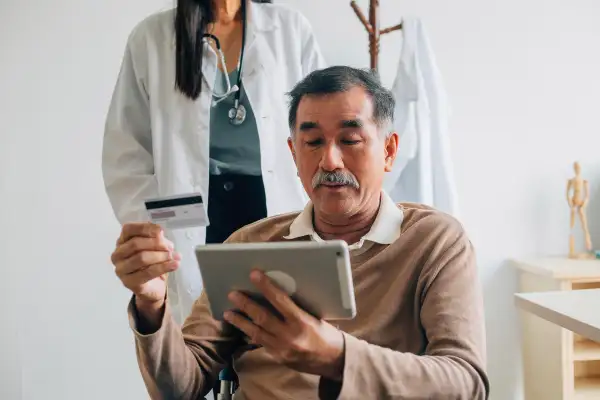 Senior man is prepared to pay with his credit card at the doctors office