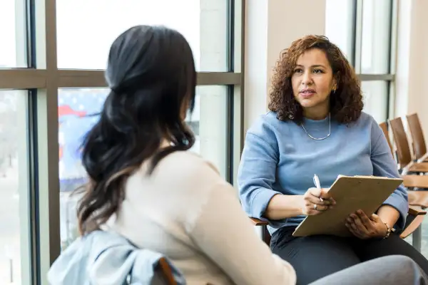 Two women, sitting next to a window, talking during a job interview