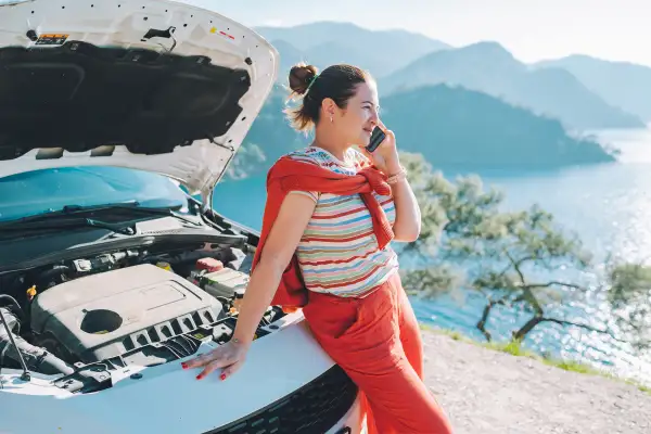 Woman making a phone call in-front of an open hood of a car