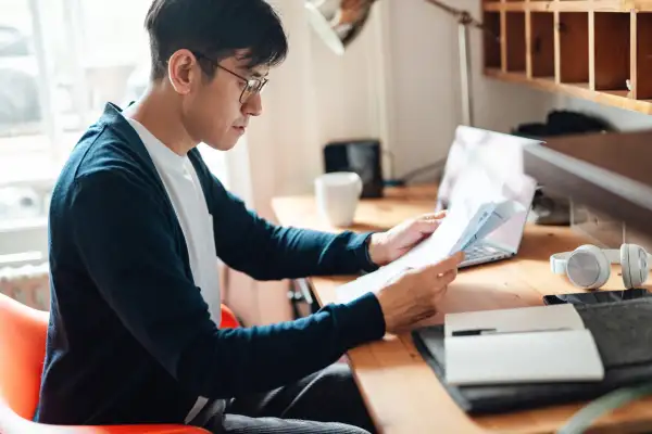 Man looking through paperwork sitting at a desk