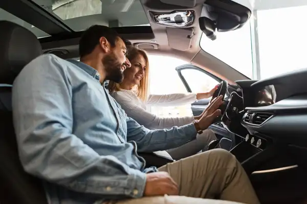 Couple inside a new car looking at the steering wheel