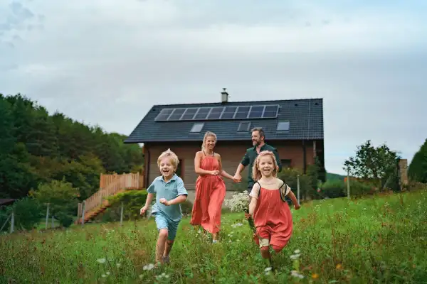 Happy family running near their house with a solar panels.