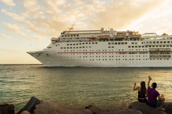 Couple sitting on rocks watching a cruise ship sailing afar