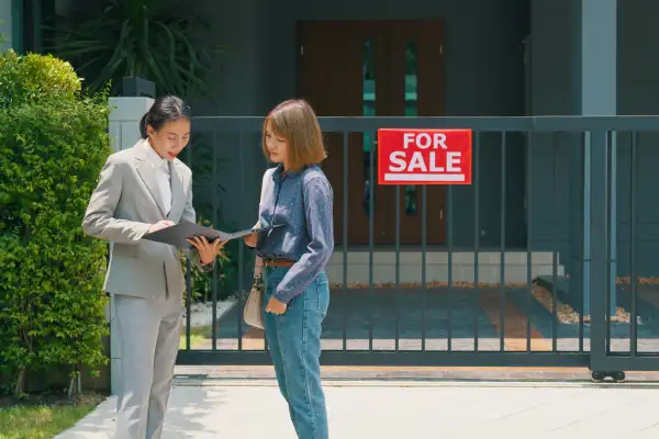 Woman real estate broker showing house to female buyers outside at home