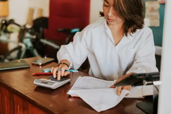 Woman lookin over bills and using a calculator