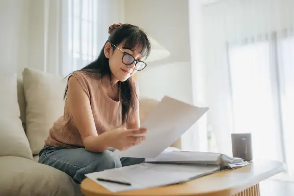 Woman sitting on a couch looking over paper documents