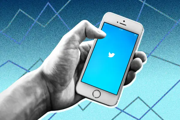 Photo collage of a hand holding a smartphone with the Twitter logo and stock graphs in the background