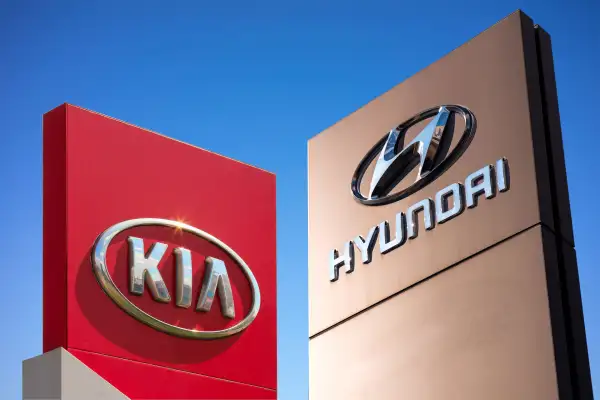 Collage of a Kia and Hyundai car brand sign with a blue sky in the background