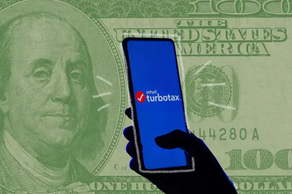 Photo illustration of a giant money bill superimposed on a hand holding a cel phone with the TurboTax app