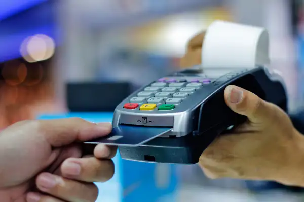 Close-up of a hand with a credit card paying through a terminal