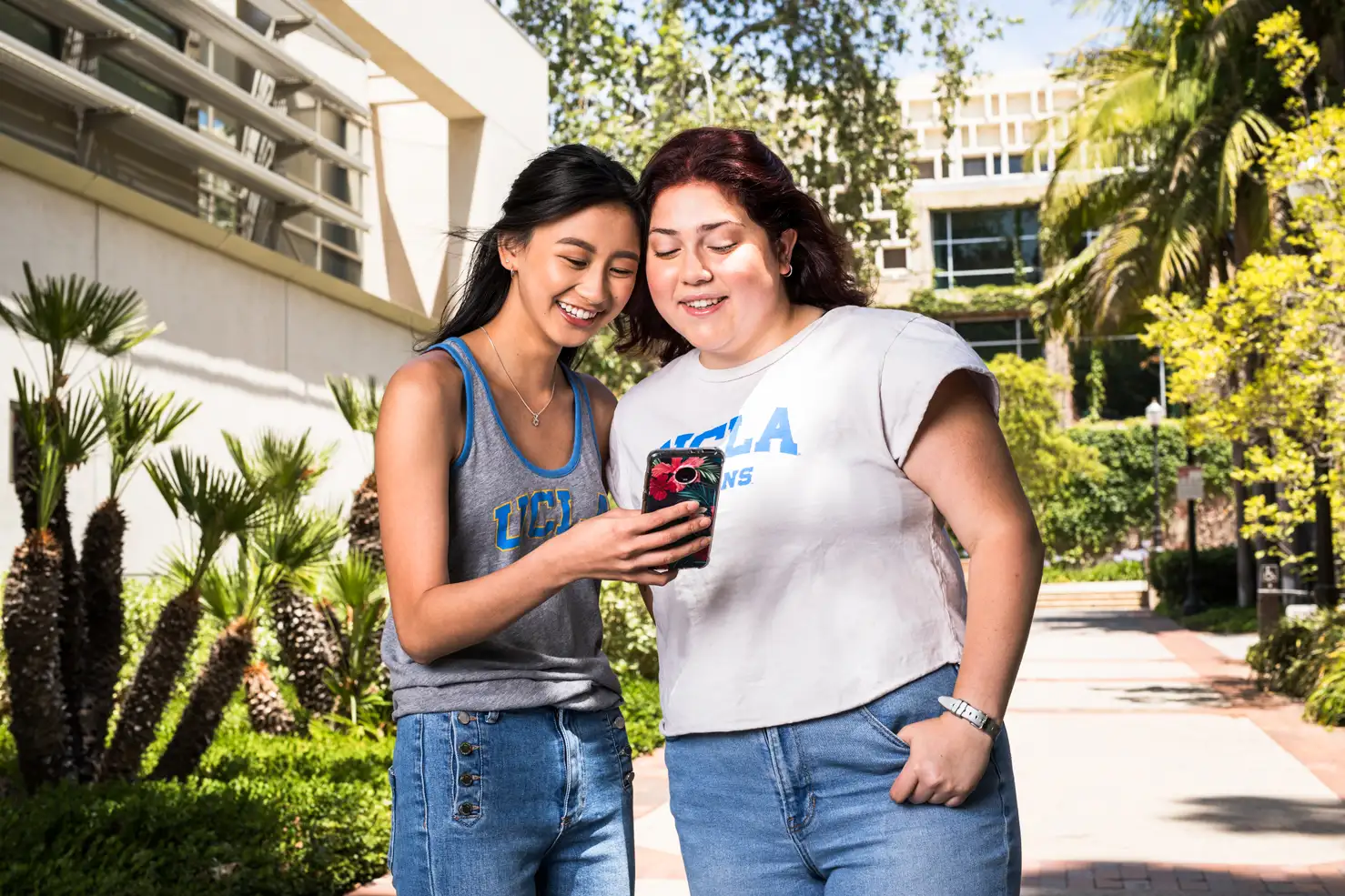 Two students on campus looking at a smartphone at UCLA