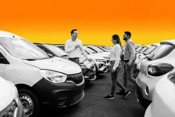 Couple and a salesman walking through new cars in a dealership