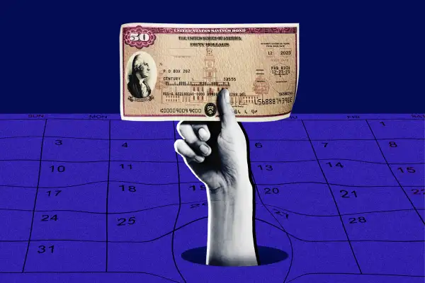 Close-up of a hand holding a U.S. Savings Bonds, coming out of a calendar