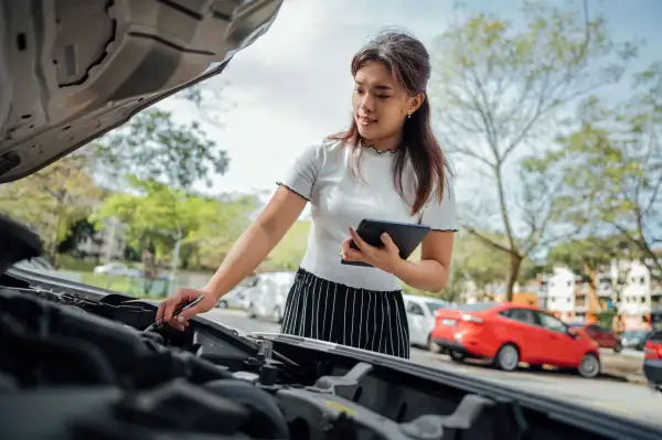 Automobile insurance adjuster using digital tablet to inspecting damage to vehicle.