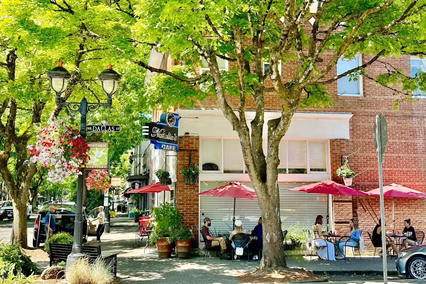 People sitting outside a cafe with trees and flowers